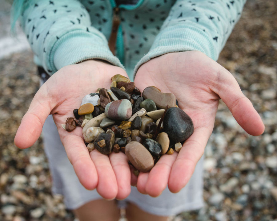 child holding small colorful pebbles